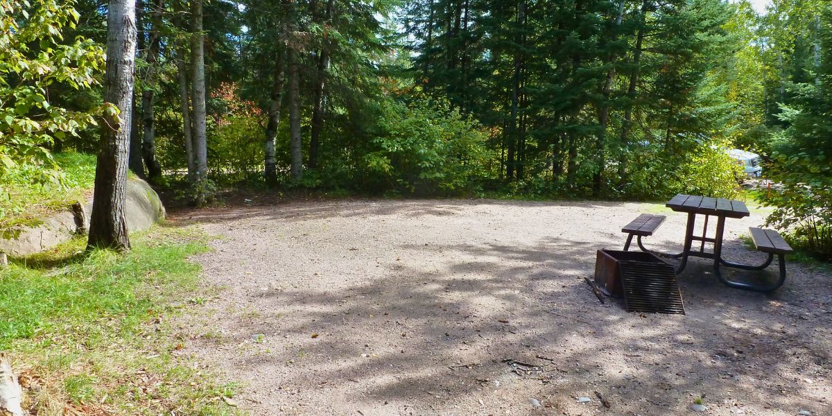 Secluded, treed campsite with a picnic table and fire pit from Big Whiteshell Campground.